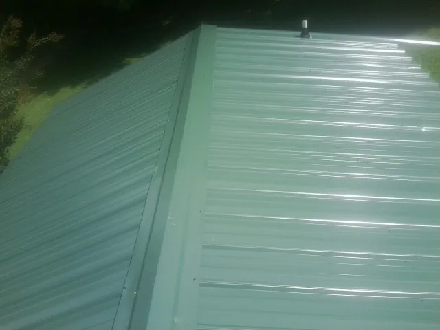 New green metal panels meeting at the ridge of a roof — Flat Roof Repair work by our crew in Walsenburg