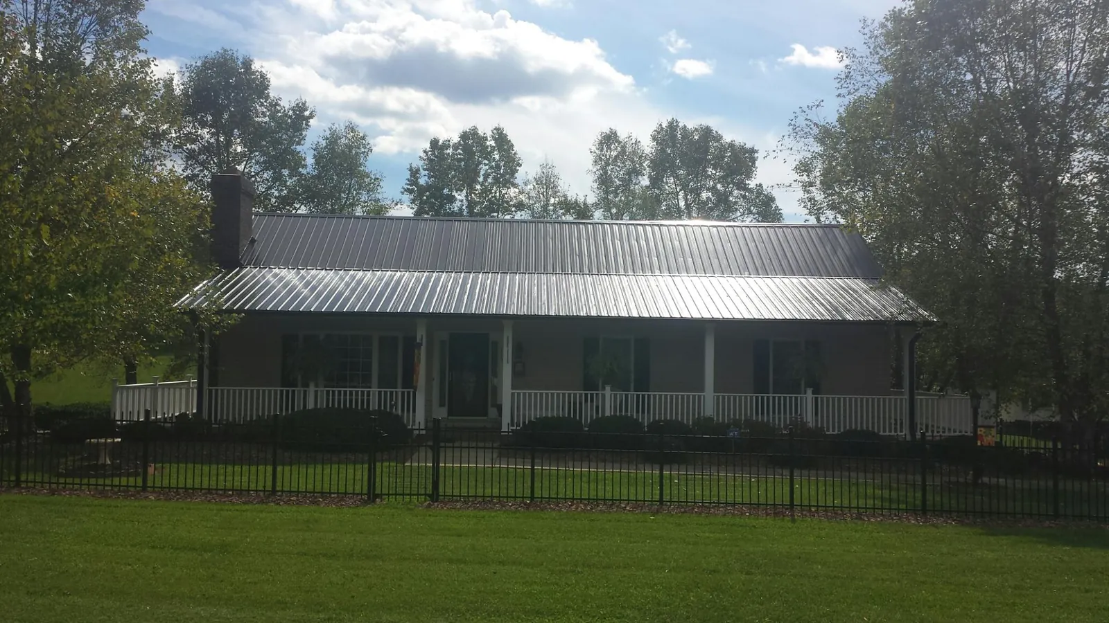 Gray metal roof on a brick ranch with a full width front porch — Gutter Guard Installation work by our crew in Walsenburg