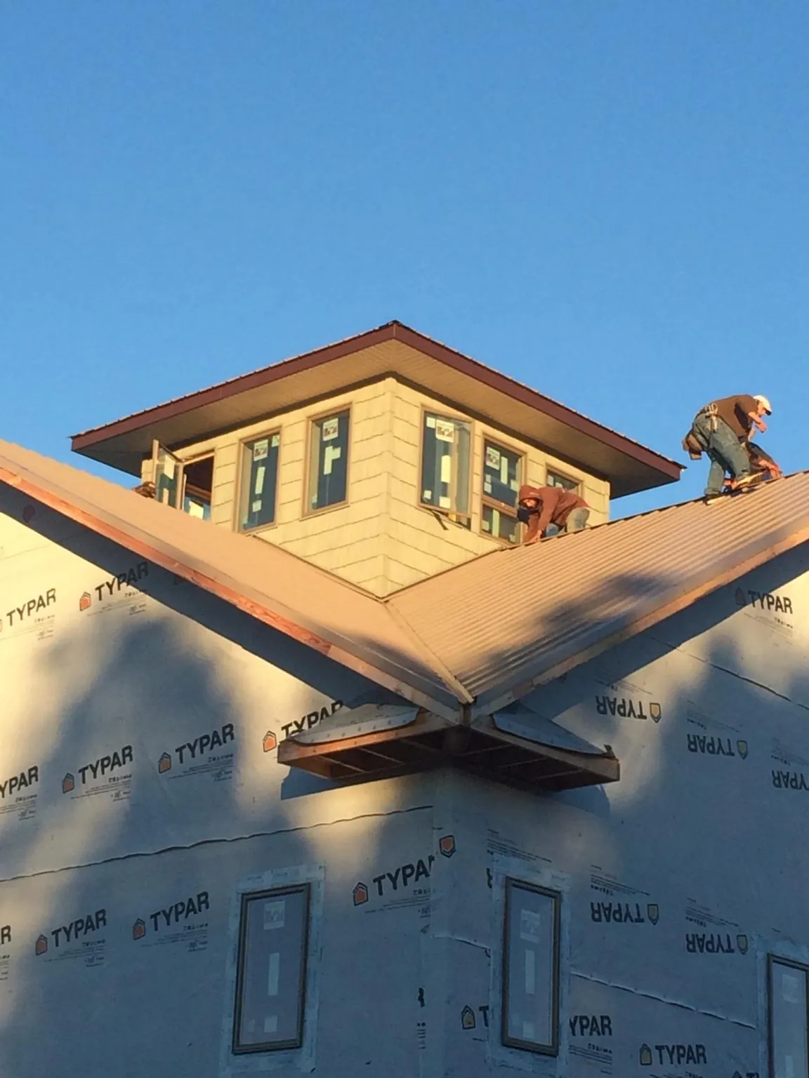 Roofers working around a rooftop cupola on a new metal roof at sunset — Roof Waterproofing in Walsenburg by Roofing Brothers